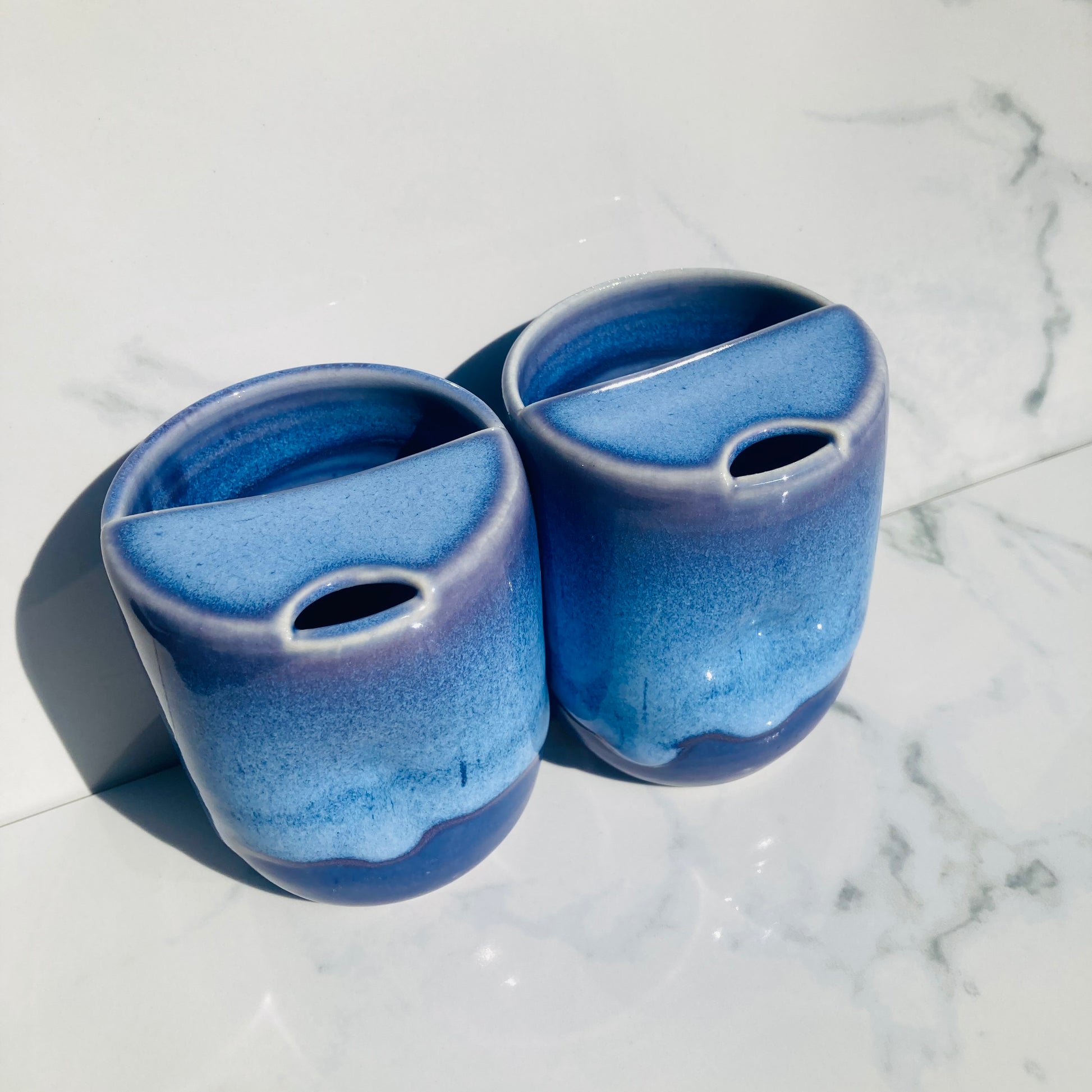 Healthy ceramic adult sippy cups in glossy indigo blue glaze on marble background